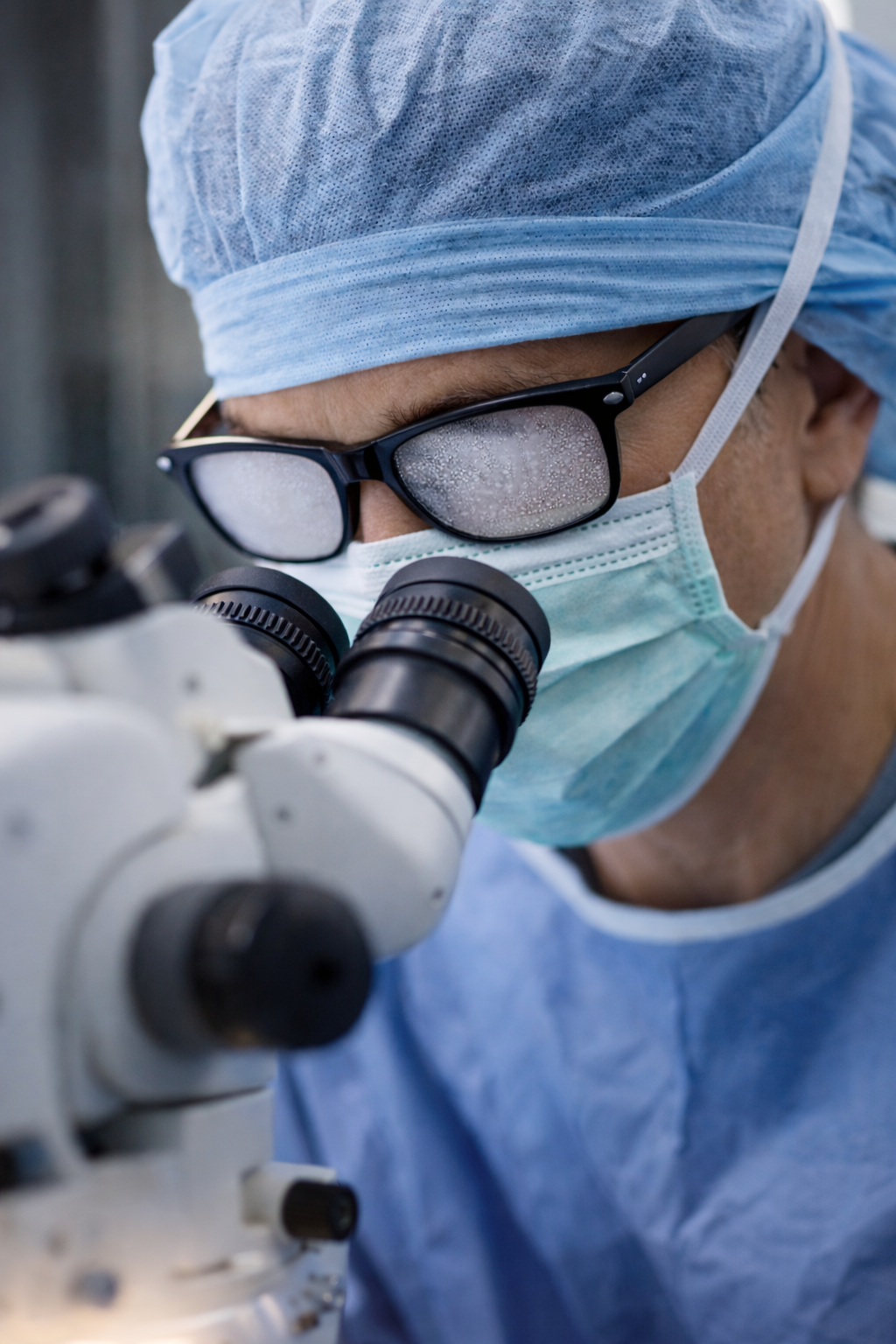 Surgeon adjusting fogged glasses while wearing a surgical mask during an operation, highlighting vision challenges in the operating theatre.